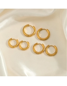 Detailed view of three pairs of golden stainless steel hoop earrings on white silk