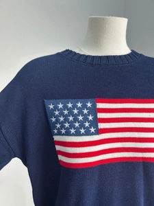 Detail of navy knit sweater showing close-up of American flag pattern and ribbed crewneck