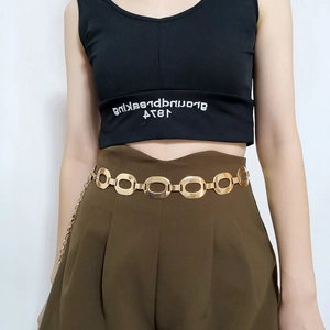 Detailed macro view of the gold oval link metal chain belt on a model's waist