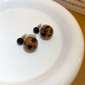 Chic leopard print sphere earrings with black beads on a minimalist white plate