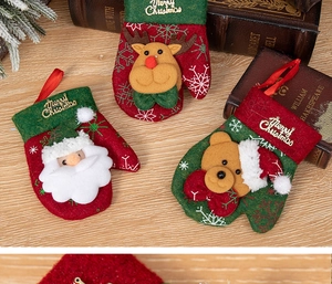 Detail view of plush Christmas stockings with Santa and elk motifs on a rustic wooden table