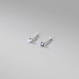 Macro shot of 999 silver four-prong stud earrings with vibrant purple round zircon
