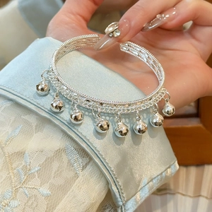 Gros plan d'un bracelet ouvert argenté orné de délicats pendentifs clochettes évidés