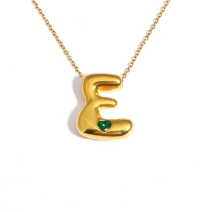 Detail of 18k gold plated bubble letter E pendant with a small green heart gemstone
