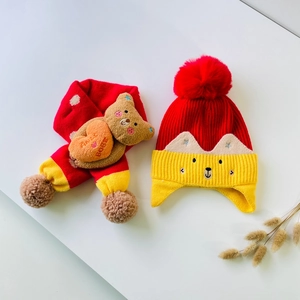 Detail of winter knit hat and scarf set with cute bear doll and red pompom for kids