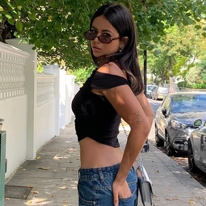 Detail of a slim-fit black off-shoulder top paired with blue jeans in a street style