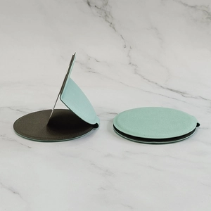 Portable mint green round leather folding mirror on a white marble surface