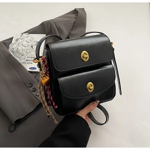 Detail of black crossbody bag with double front flap pockets and golden twist locks