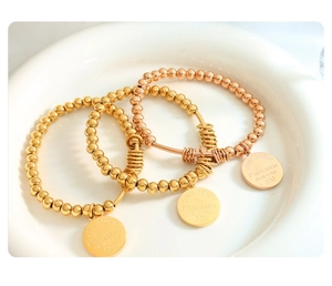 Detailed macro of gold and rose gold beaded bracelets with engraved round pendants