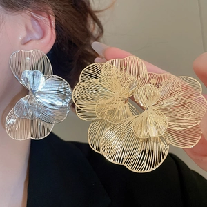 Gros plan sur les boucles d'oreilles fleurs en métal avec pétales en maille dorée