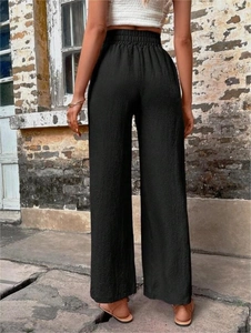 Détail d'un pantalon large noir à taille haute avec une texture de tissu grainé unique