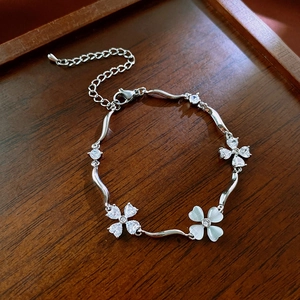 Macro shot of silver zircon flower bracelet with wave chain on dark wood tray
