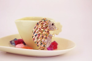 Close-up of a gold hedgehog keychain with sparkling colorful rhinestones on a pink base