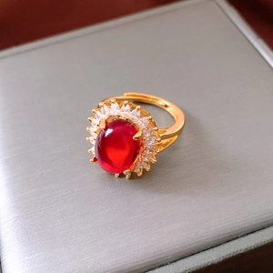 Macro view of a 24k gold-plated halo ring with red oval stone and white crystals