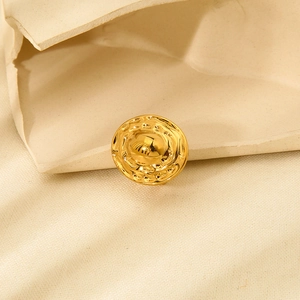 Detailed view of gold plated stainless steel earring with hammered texture on beige paper