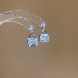 Macro shot of silver padlock earrings with square zircon and crystal pavé details