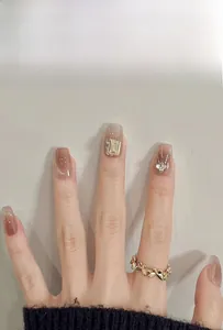 Detailed close-up of nude gradient press-on nails with 3D diamond and glitter accents