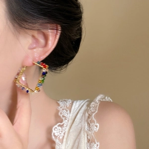 Macro detail of geometric rhombus earring with colorful beads on wire-wrapped metal frame