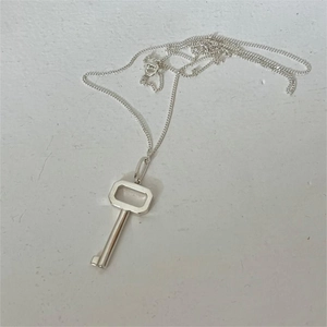 Macro detail of a 925 sterling silver key pendant necklace with a minimalist link chain