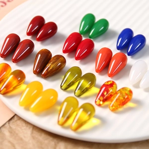 Macro shot of 26 colorful teardrop resin charms for jewelry making on a white ceramic plate