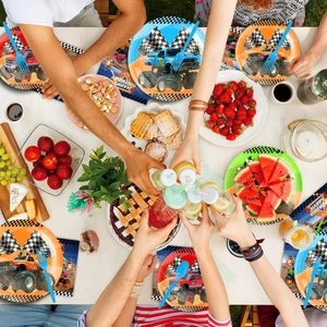 Detail of monster truck party plates, napkins, and blue cutlery on a wooden birthday table