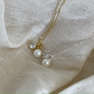 Detail of gold and silver pearl necklaces with cubic zirconia on natural linen fabric