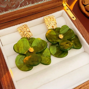 Macro detail of forest green acrylic flower earrings with hammered gold metal base