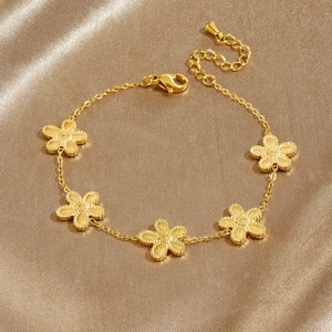 Exquisite gold stainless steel bracelet with five petal flower charms on silk background