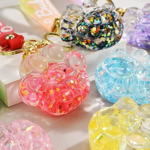 Close-up of cat paw acrylic keychain with glitter star sequins and silicone wrist strap