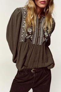 Detail of bohemian floral embroidery and fabric buttons on green long sleeve linen shirt