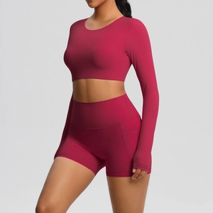 Detail van high-waist yogashorts met zijzakken en crop top met lange mouwen in donkerrood