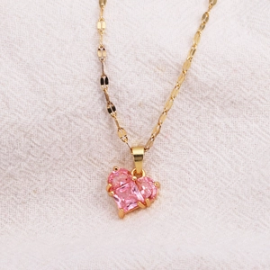 Macro view of gold chain necklace featuring a pink faceted heart-shaped gemstone pendant