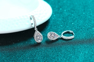 Macro shot of silver teardrop earrings with pear-cut moissanite and micro-pave setting