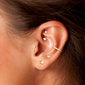 Detail of gold geometric S925 silver ear studs with cubic zirconia and pearls on ear