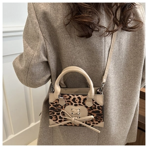 Detail of leopard print crossbody bag with beige heart patch and bow on wool coat
