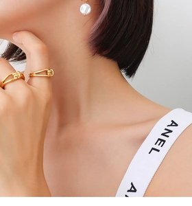 Close-up of gold twist rings and asymmetric pearl earrings on a model in French style