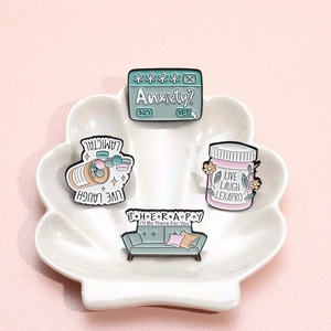 Set of 4 mental health enamel pins with supportive quotes in a white shell dish