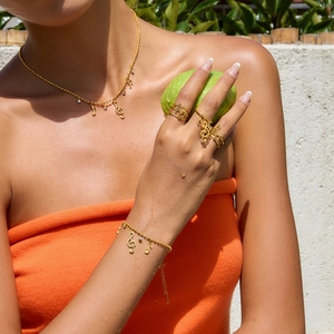 Close-up of 18K gold plated musical note necklace and bracelet set on a model