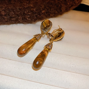 Vintage gold drop earrings with amber stone and rhinestones on textured fabric