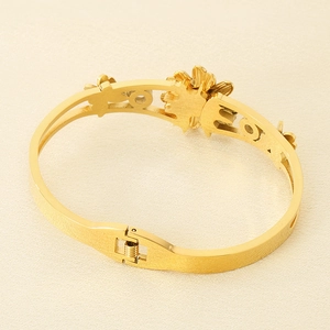 Gros plan du bracelet floral ajouré doré avec fermoir à ressort sur tissu clair