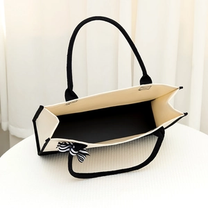 Canvas tote bag in beige with black trim and elegant bow detail on handle