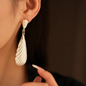 Gros plan sur des boucles d'oreilles vintage en émail blanc avec détails dorés rayés