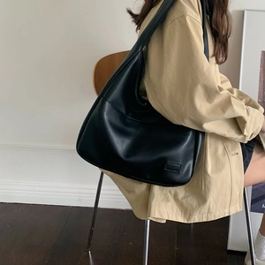 Minimalistische schwarze PU-Leder-Einkaufstasche an einem Model im beigen Trenchcoat