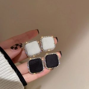 Close-up of square houndstooth stud earrings with sparkling crystals and gold trim