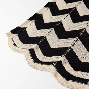 Detail aus schwarz-weiß gestreiftem Strickstoff mit dekorativem Wellensaum-Design