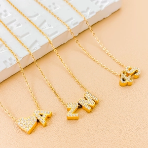 Macro detail of gold plated letter pendants A, Z, M, S with sparkling cubic zirconia
