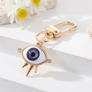 Close-up of golden Evil Eye keychain with blue iris, resin insert and sparkling crystals