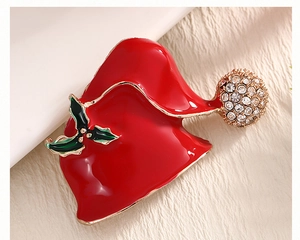 Detail of red enamel Christmas hat brooch with holly leaves and sparkling rhinestones