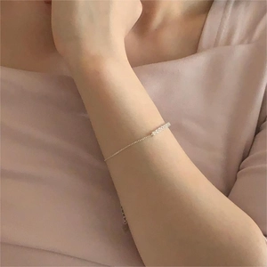 Close-up of a minimalist S925 silver bracelet with sparkling zircon bar on woman's wrist