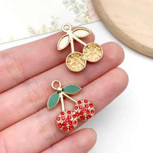 Detailed close-up of mini crystal cherry pendants for DIY jewelry making held by fingers